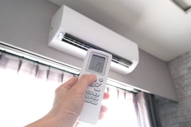Technician checking airflow and thermostat settings in Massapequa home with uneven cooling