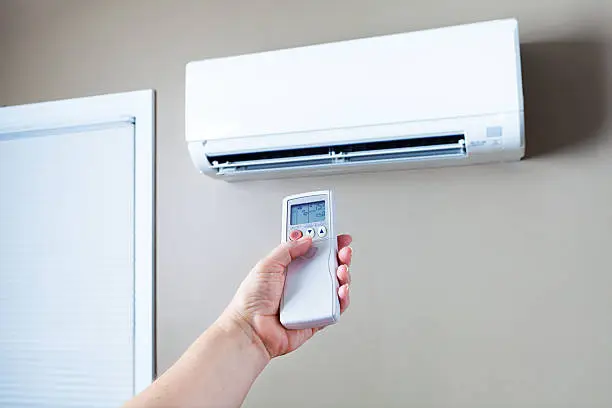 Technician servicing outdoor AC unit beside Mineola home during summer cooling problem