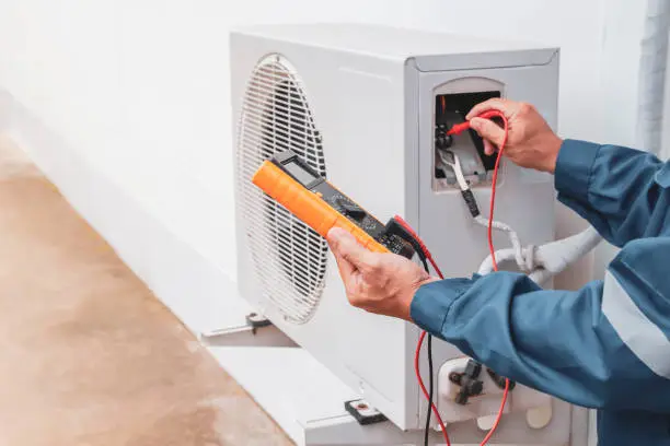 Experienced HVAC technician inspecting electrical connections and airflow readings during maintenance visit, Technician performing HVAC maintenance on an indoor air handler in a Patchogue - NY basement