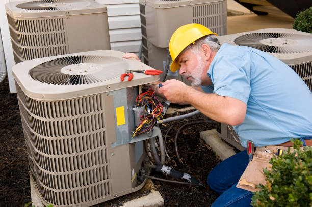 Experienced HVAC technician measuring airflow and checking electrical connections during maintenance service, Commercial HVAC in Garden City - NY with a technician inspecting rooftop equipment above a retail building